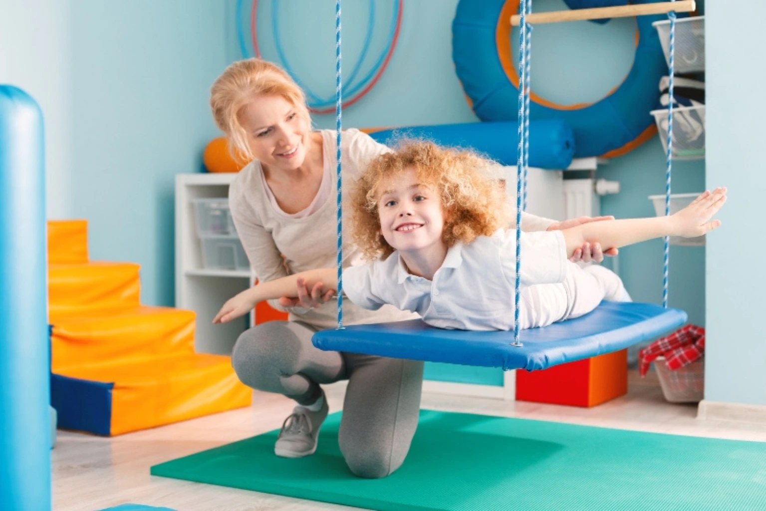 Fisioterapeuta realizando terapia de integración sensorial con niño con autismo en sala de fisioterapia infantil