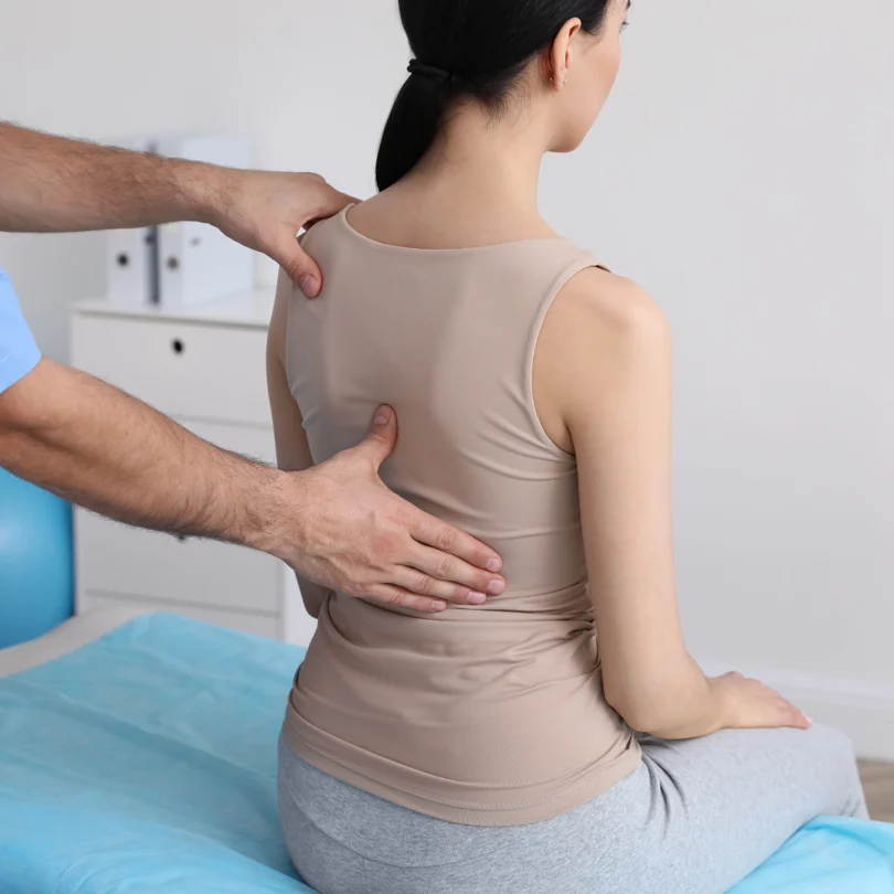 Fisioterapeuta aplicando electroestimulación y técnicas manuales en la espalda de un paciente